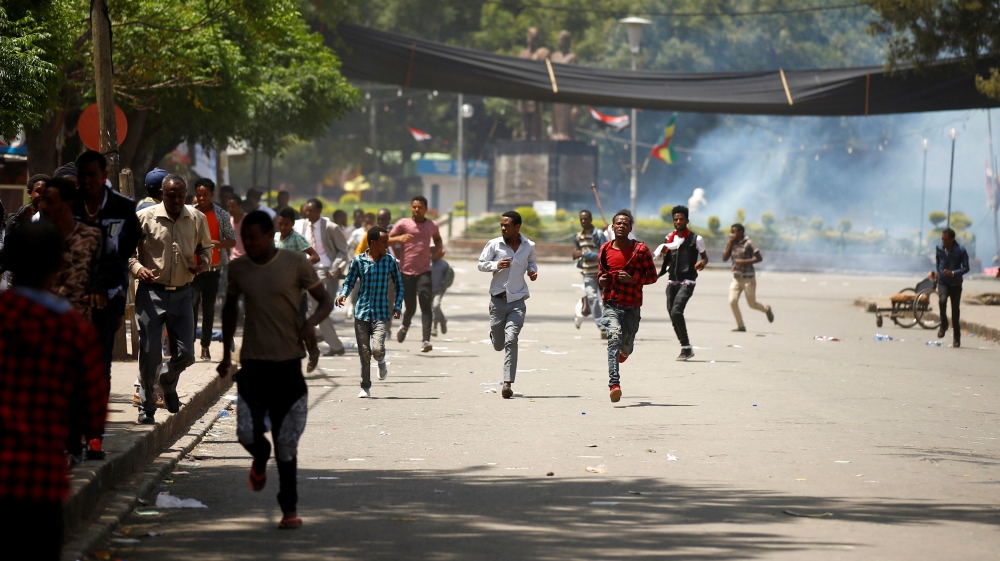 Protesters run from tear gas being fired by police during Irreecha, the religious festival in Bishoftu where at least 52 people died [Tiksa Negeri/Reuters]