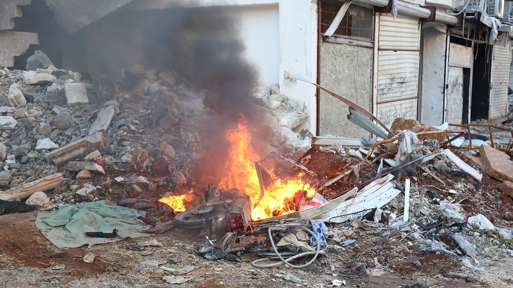 A resident of east Aleppo burns his motorcycle before fleeing, to prevent regime forces from using it [Malek Al Shimale/Al Jazeera]