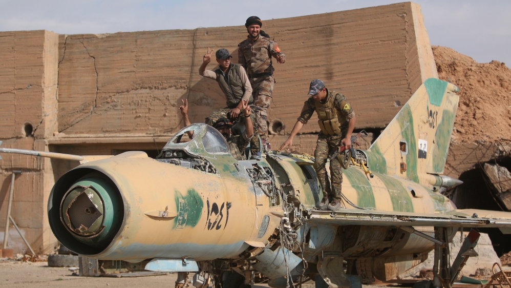 Syrian Democratic Forces (SDF) fighters gesture while posing on a damaged airplane inside Tabqa military airport after taking control of it from Islamic State fighters, west of Raqqa city