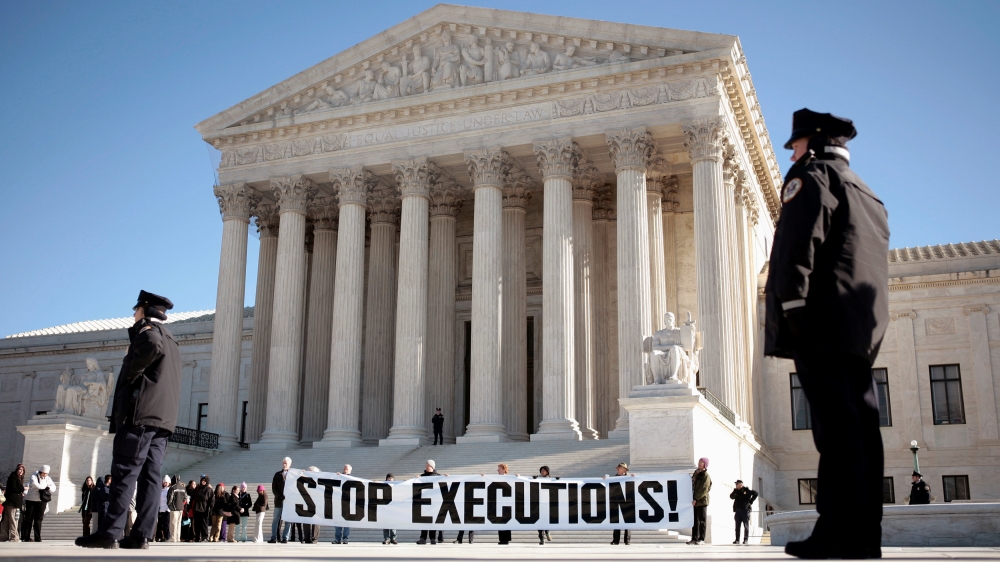 FILE PHOTO: Protesters unfurl a banner as police look on outside the U.S. Supreme Court in Washington