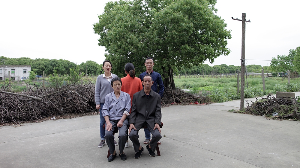 Cai Fengxia (facing away from the camera) with her birth parents, older sister and younger brother [Han Meng/Al Jazeera]