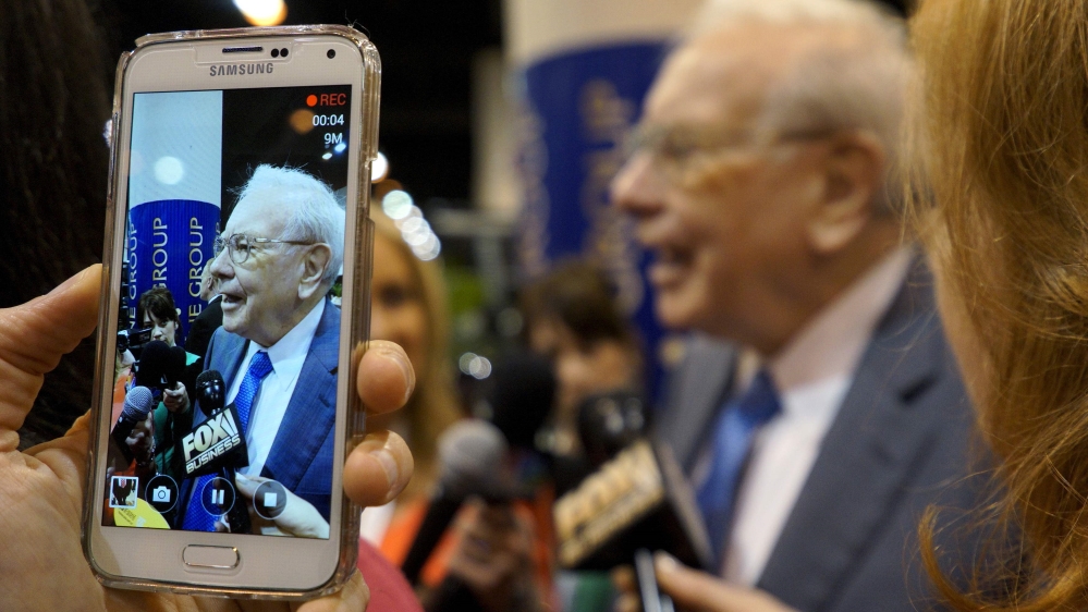 Berkshire Hathaway CEO Warren Buffett is seen on a cellphone camera as he talks to reporters prior to the Berkshire annual meeting in Omaha