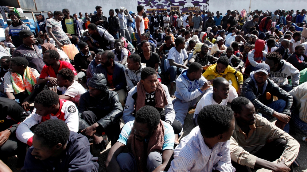 Illegal African migrants sit during a visit by Martin Kobler and William Lacy Swing at a detention camp in Tripoli