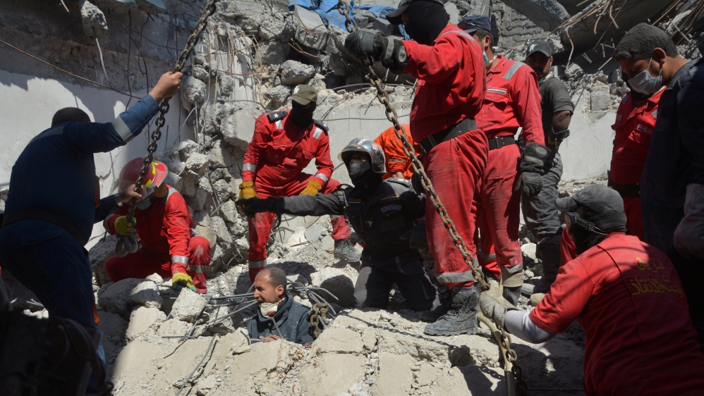 Iraqi firefighters look for bodies buried under the rubble, of civilians who were killed after an air strike against Islamic State triggered a massive explosion in Mosul