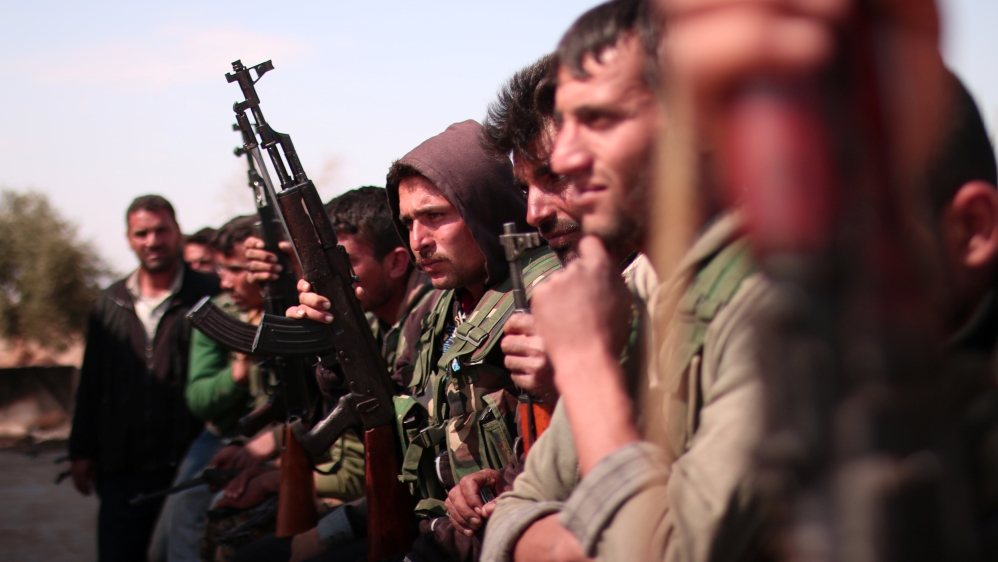 Syrian Democratic Forces(SDF) fighters stand with their weapons north of Raqqa city