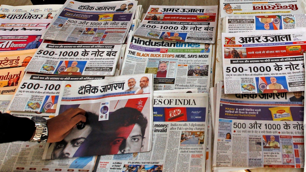 A man reads a cover story in a daily national newspaper about the withdrawal of 500 and 1000 rupee banknotes from circulation across India, at a roadside stall in Allahabad