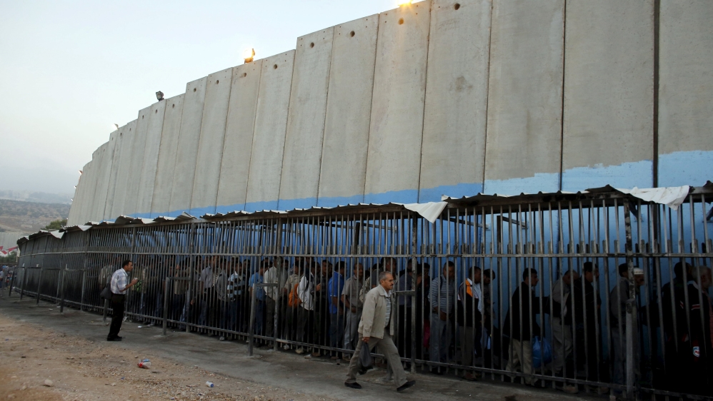 File photo shows Palestinians waiting to cross into Jerusalem next to Israel''s controversial barrier at an Israeli checkpoint in Bethlehem