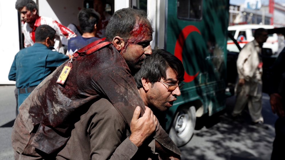 An Afghan man carries an injured man to a hospital after a blast in Kabul, Afghanistan