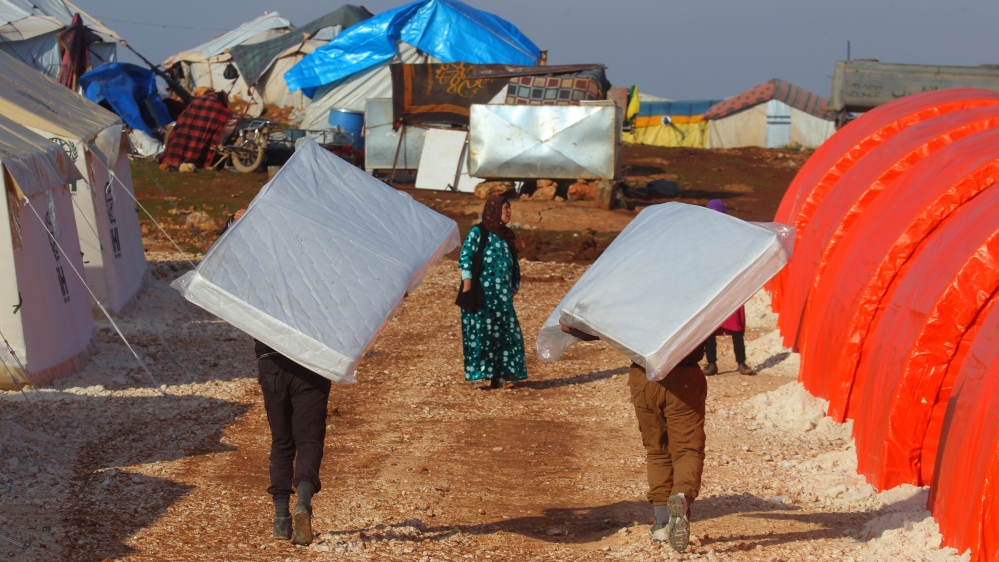 Evacuees from a rebel-held area of Aleppo carry mattresses they received as aid in al-Kamouneh camp, Idlib province