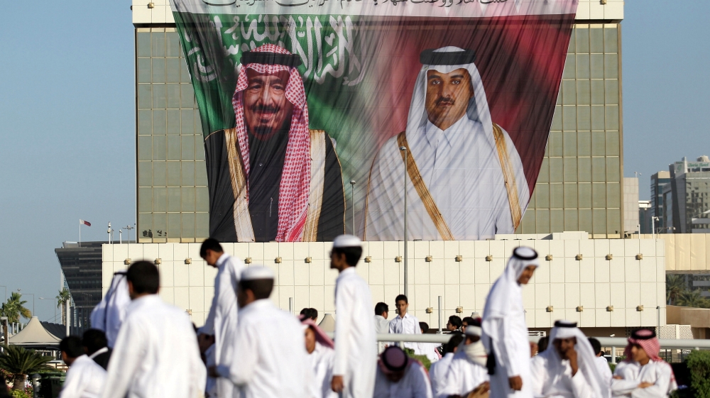 People gather in front of a poster depicting Saudi King Salman and Qatar''s Emir Sheikh Tamim Bin Hamad Al-Thani during a welcoming ceremony for King Salman at the Royal Court on Doha Corniche