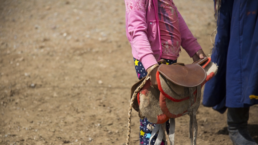 Bujinlkham Damdinsuren prepares a saddle for her horse during her last training ride before the 24km race [Hannah Griffin/Al Jazeera]