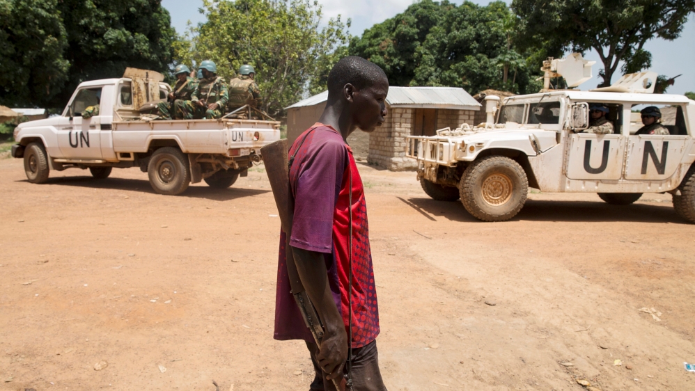 Member of the Anti-Balaka armed militia walks next to United Nations peacekeeping soldiers in the village of Makunzi Wali, Central African Republic