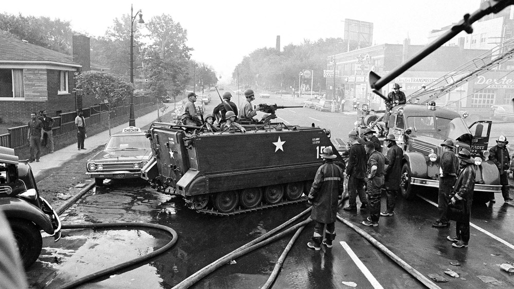 National Guardsmen, called in to restore order by Governor George Romney, stop their vehicle near a Detroit fire truck in the neighbourhood that was ravaged by rioting the previous day. [File: The Associated Press]
