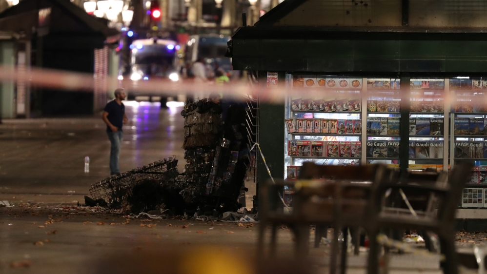 A officer walks past a fallen post cards display near the area where a van crashed into pedestrians at Las Ramblas in Barcelona