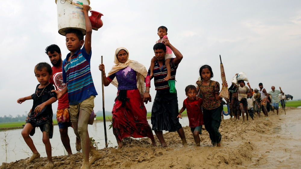 Rohingya refugees walk on the muddy path after crossing the Bangladesh-Myanmar border in Teknaf