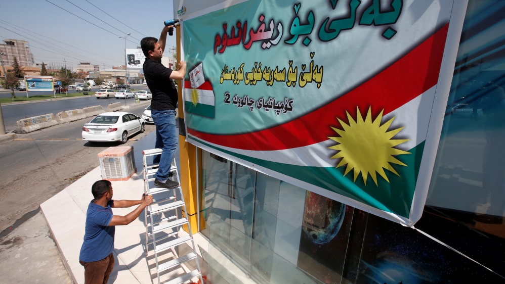 Kurdish man hangs up banner urging people to vote for independence referendum, in Erbil