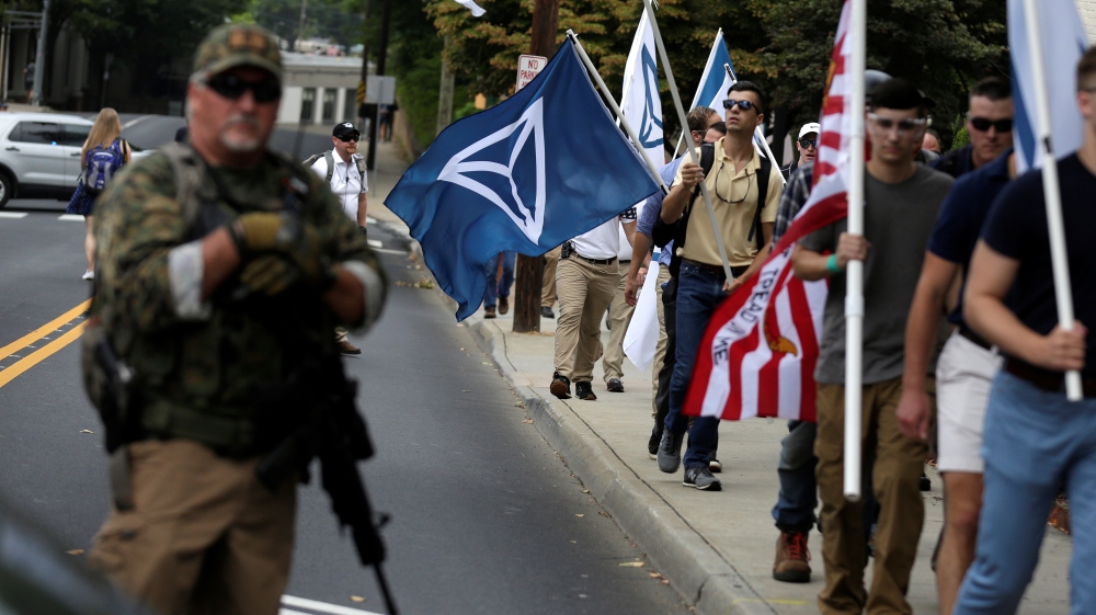 White nationalists pass a militia member as the they arrive for a rally in Charlottesville Virginia