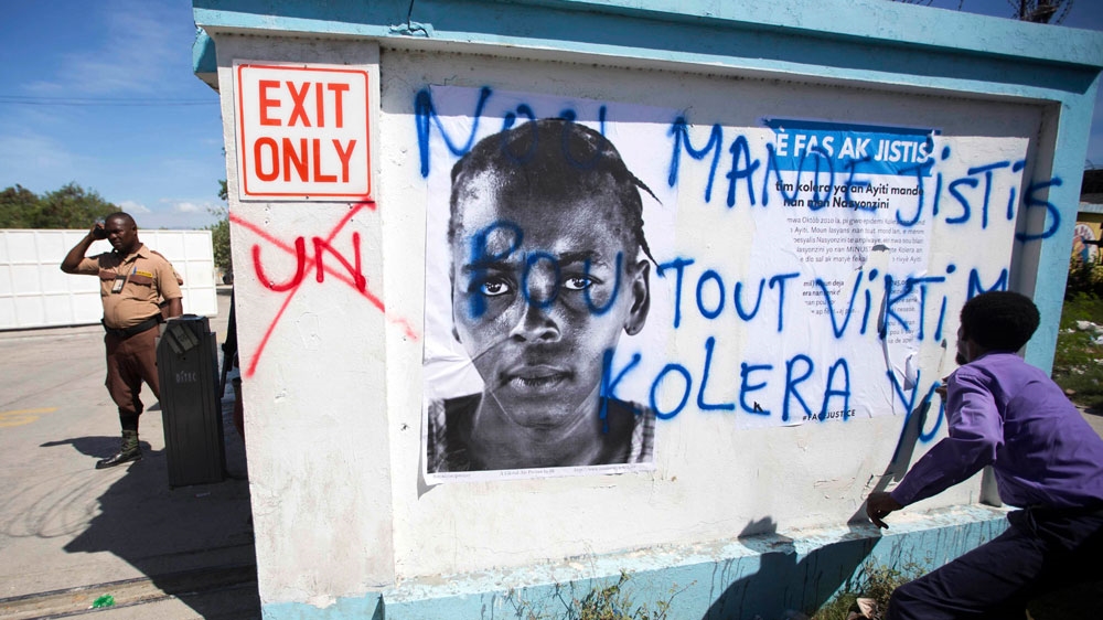 A demonstrator spray paints the message in Creole 