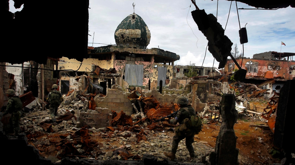 Government soldiers patrol past damaged buildings as troops continue their assault on clearing operations against the pro-IS militant group in Marawi city