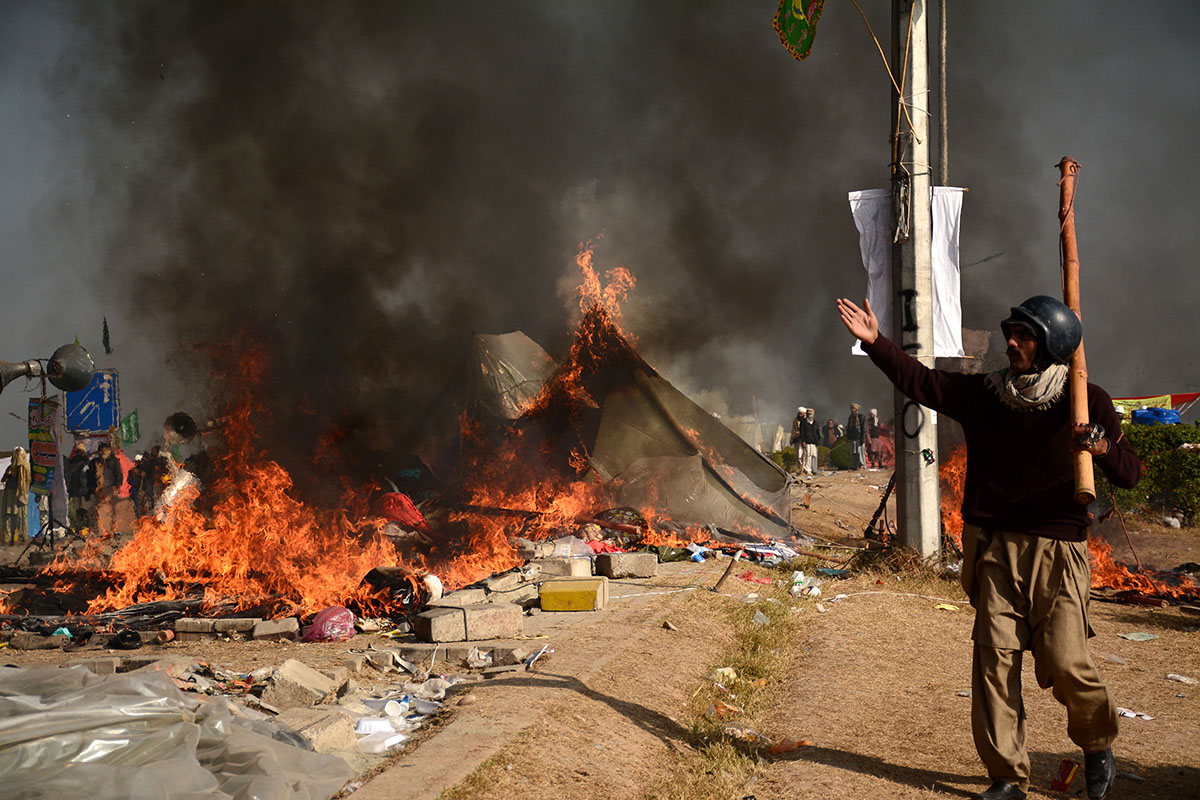A protester walks near burning tents during clashes with police at Faizabad junction in Islamabad, Pakistan November 25, 2017. REUTERS/Stringer