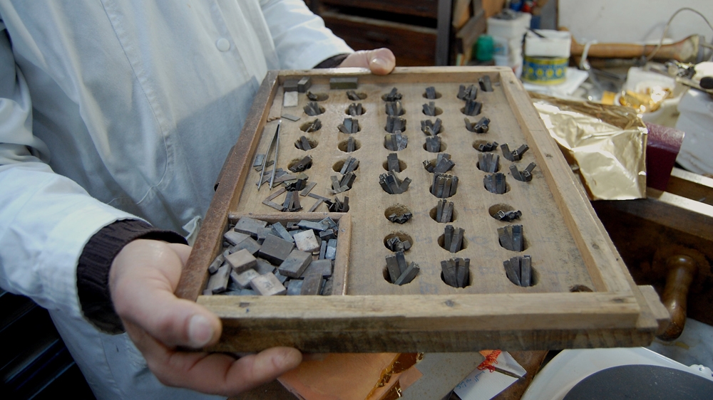 He also heats pieces of metal to stamp lines onto the book covers [Jillian Kestler-D'Amours/Al Jazeera]