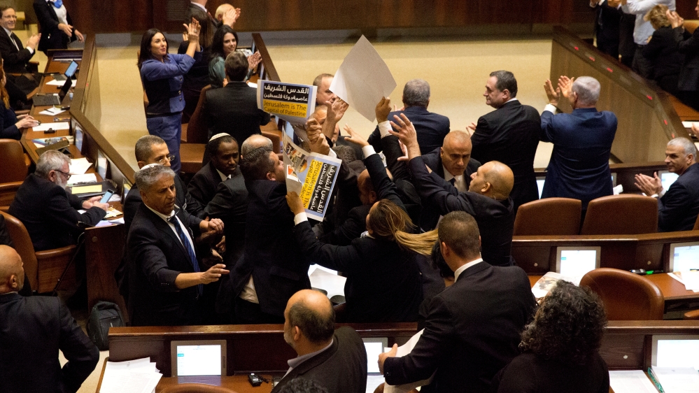 Ushers scuffle with members of the Joint Arab List who held protest signs before Pence's Knesset address [Ariel Schalit/Reuters]