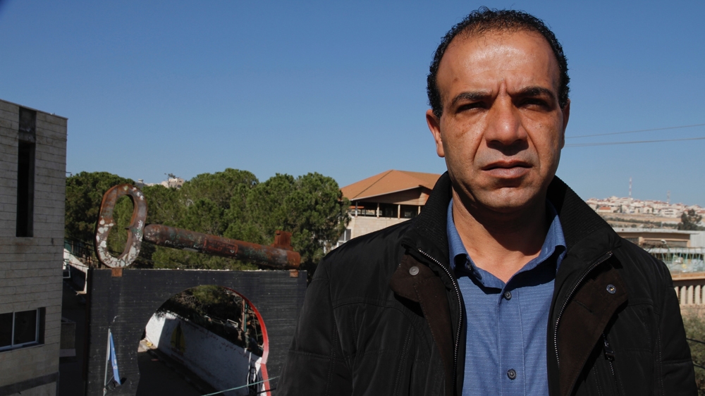 Salah Ajarmeh with the iconic key at the entrance to Aida camp, symbolising the Right of Return [Ibrahim Husseini/Al Jazeera]