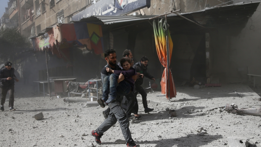 A man runs as he holds a girl after an airstrike in the besieged town of Douma in eastern Ghouta in Damascus