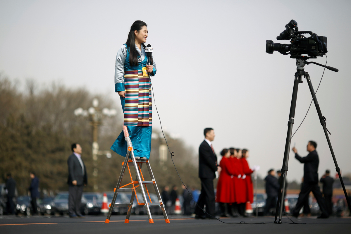 A journalist reports on a ladder outside the Great Hall of the People during the opening session of the National People''s Congress (NPC) in Beijing, China March 5, 2018. REUTERS/Thomas Peter TPX IMAGE