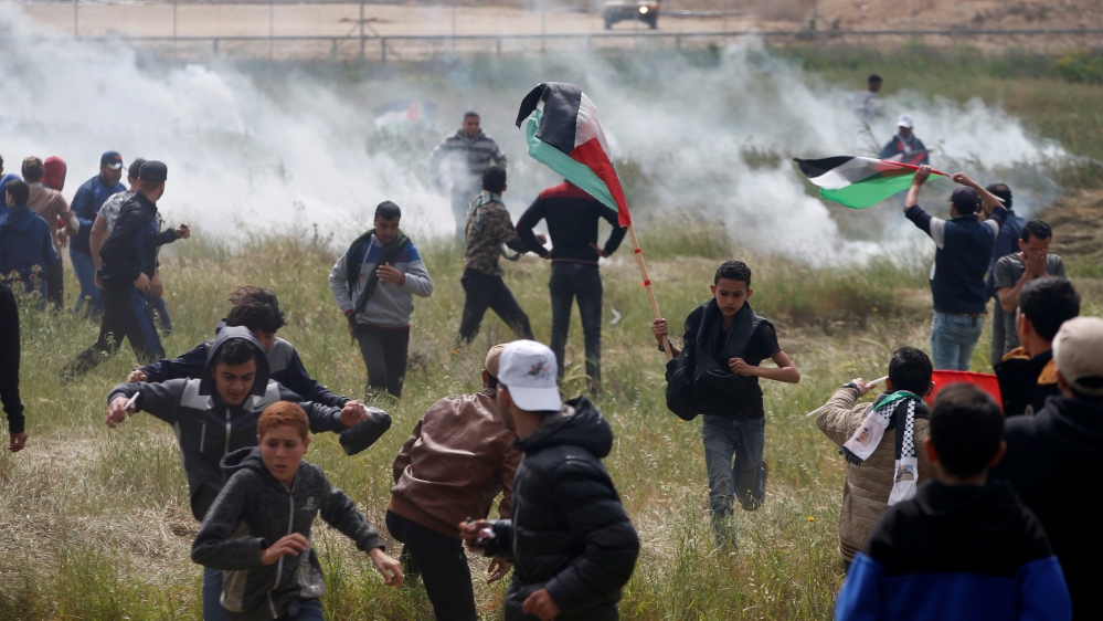 Palestinians run from tear gas fired by Israeli troops during clashes, during a tent city protest along the Israel border with Gaza, demanding the right to return to their homeland, east of Gaza City