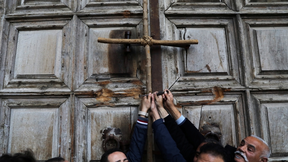 Worshippers hold a cross during a protest in front of the closed doors of the Church of the Holy Sepulchre in Jerusalem''s Old City