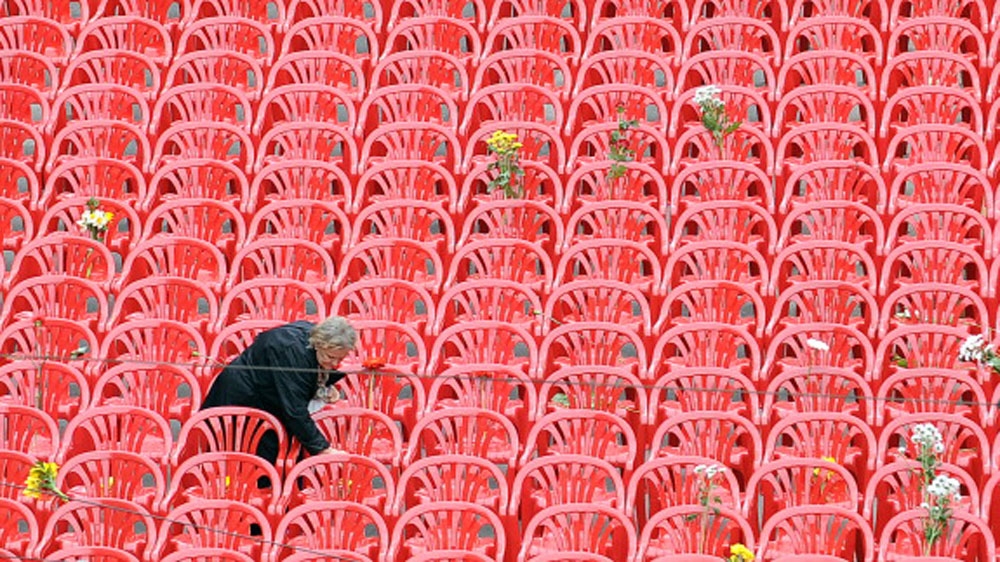 A woman lays flowers on one of 11,000 red chairs that lined Sarajevo's main avenue, symbolising the at least 11,541 victims of the siege [Elvis Barukcic/EFP/Getty Images] 