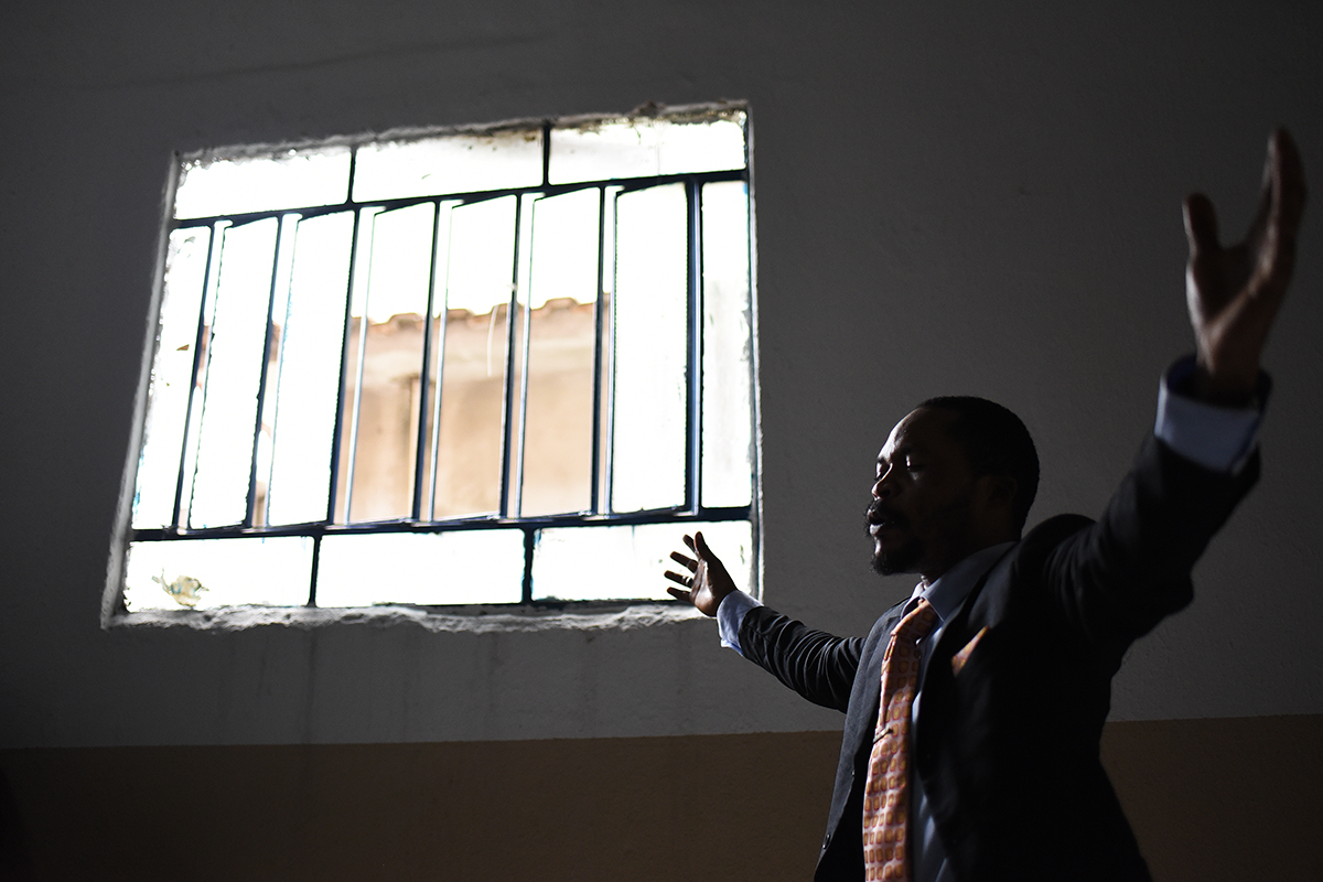 A refugee from the Democratic Republic of Congo praying during a Christian service at a church in the Bras de Pina favela. The Congolese face racism, poverty and unemployment in favelas dominated by d