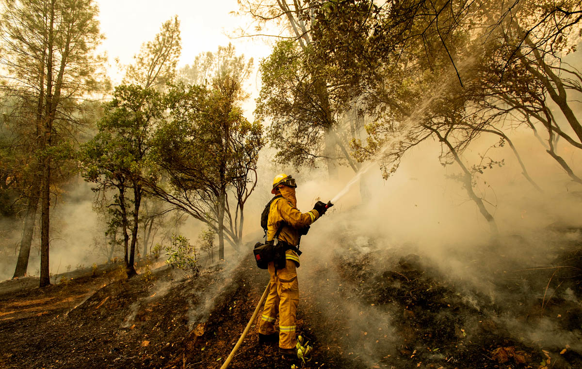 Firefighter Scott Brown sprays water on a backfire while battling the Carr Fire in Redding, Calif., on Saturday, July 28, 2018. (AP Photo/Noah Berger)