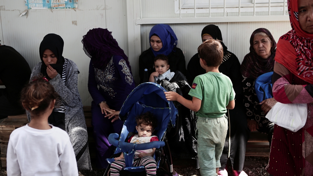 Women and children sit at the Moria camp for refugees and migrants on the island of Lesbos [Elias Marcou/Reuters]