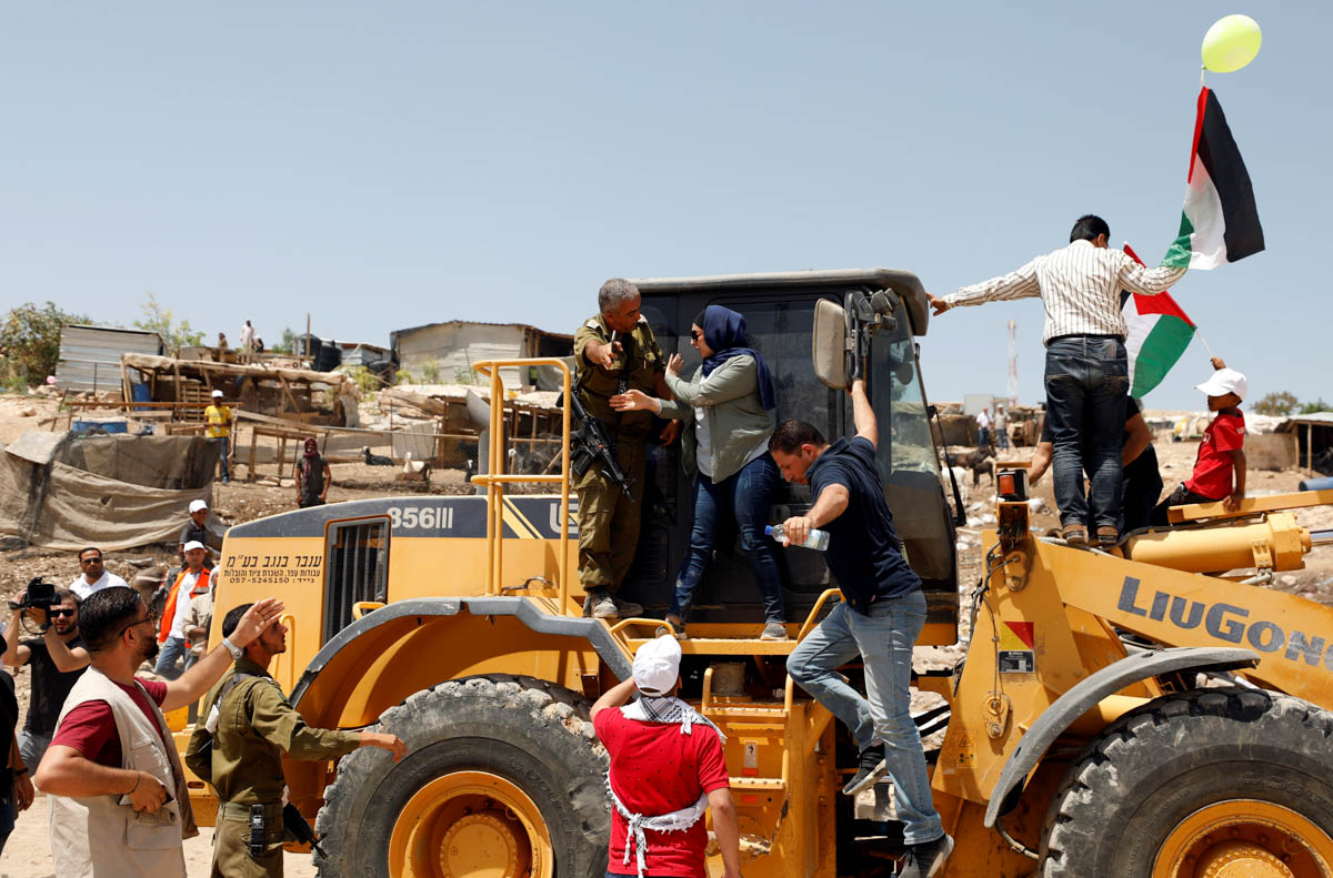 A Palestinian woman argues with an Israeli soldier as she rides on an Israeli bulldozer in the Palestinian Bedouin village of al-Khan al-Ahmar near Jericho in the occupied West Bank July 4, 2018. REUT