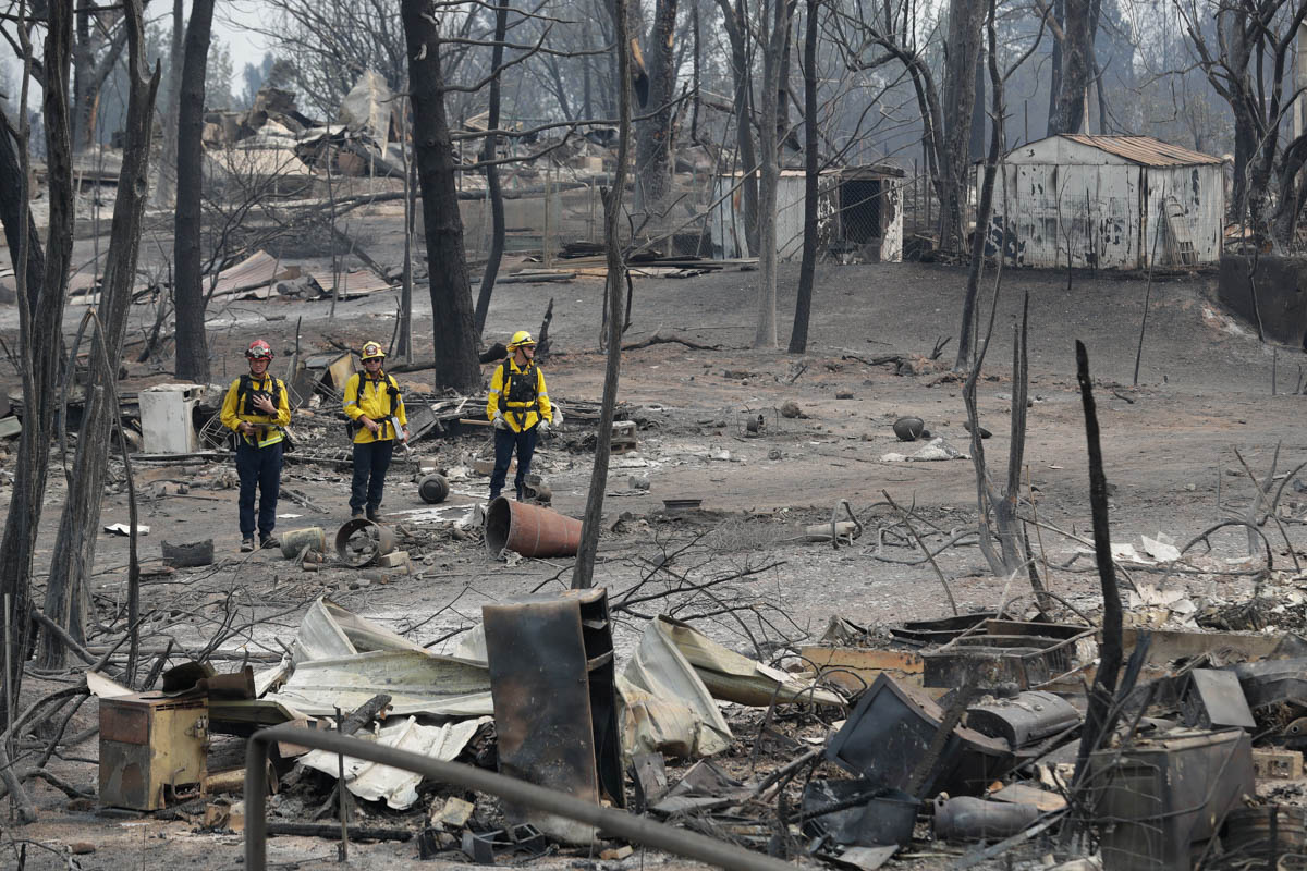San Bernardino County Fire department firefighters assess the damage to a neighborhood in the aftermath of a wildfire, Sunday, July 29, 2018, in Keswick, Calif. (AP Photo/Marcio Jose Sanchez)