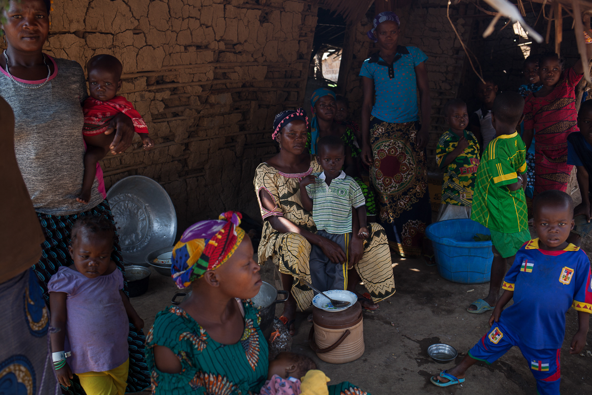 A family sits and eat in the shadow of Emmanuel Bale Nguia’s house, in Bombe Chateau. Native from CAR, Emmanuel fled his village in 2013. The rest of his family of 40 people joined him in Cameroon on