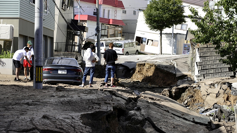People inspect an area damaged by an earthquake in Sapporo on Hokkaido island [Kyodo/via Reuters]