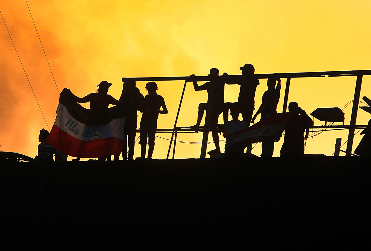 Protesters raise an Iraqi flag over the Basra Government building during a demonstration demanding better public services and jobs in Basra, 340 miles (550 km) southeast of Baghdad, Iraq, Friday, Sept