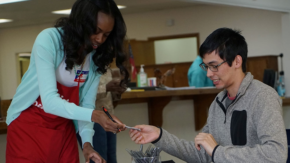 A voting official hands back an early voter his ID in Valdosta, Georgia [Lawrence Bryant/Reuters] 