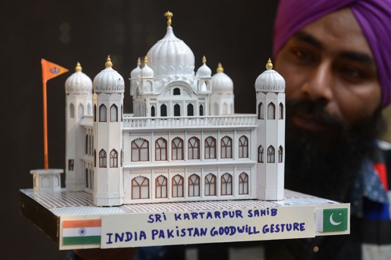 Indian artist Gurmeet Singh poses with a paper model of the Gurdwara Kartarpur Sahib in Pakistan [Narinder Nanu/AFP]