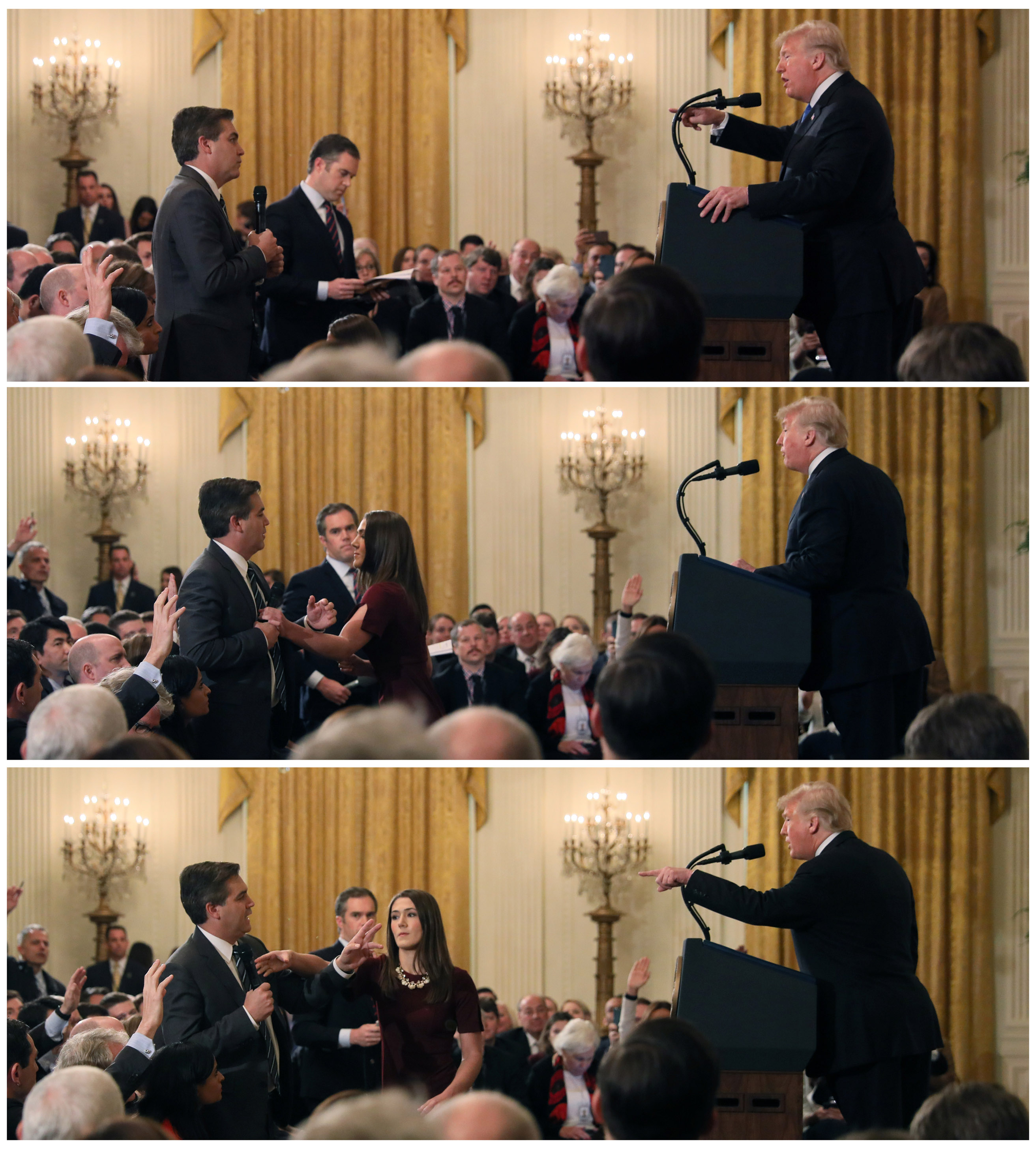 A White House staff member reaches for the microphone held by CNN's Jim Acosta as he questions US President Donald Trump [Jonathan Ernst/Reuters]