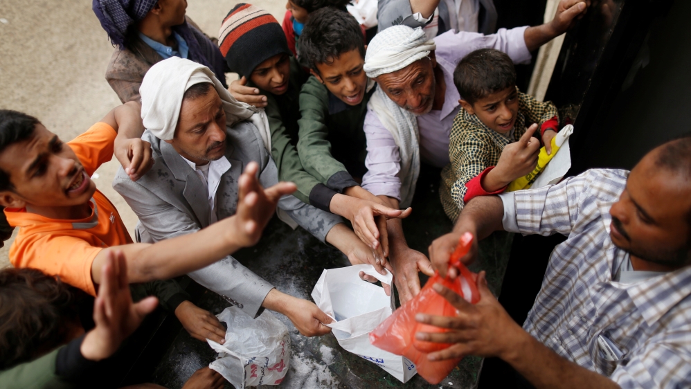 People gather to collect food rations at a food distribution center in Sanaa, Yemen