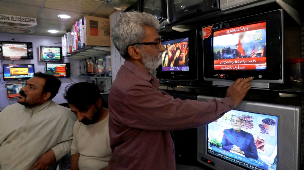 A man looks at a television screen, after Pakistan shot down two Indian planes, at a shop in Karachi