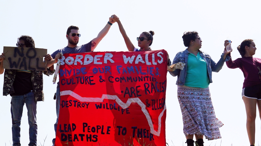 Border wall protesters link hands during a protest march at the National Butterfly Center wildlife preserve near the Rio Grande River in Mission