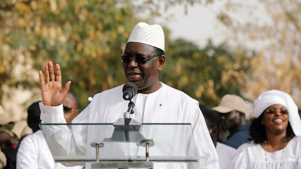Senegal's President Macky Sall speaks after casting his vote at a polling station as his wife Marem Faye Sall stands behind in Fatick