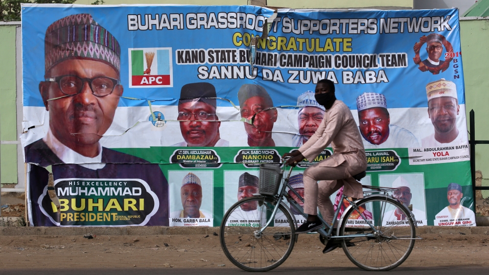 A cyclist drives pasts a campaign poster for President Muhammadu Buhari in a street after the postponement of the presidential election in Kano