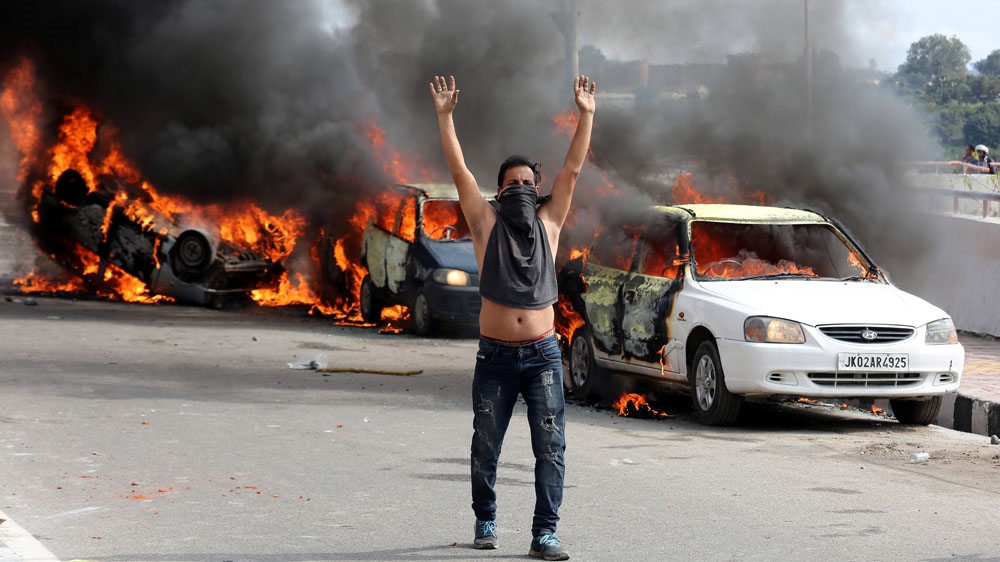 A demonstrator reacts next to burning cars during a protest in Jammu against the suicide attack [Mukesh Gupta/Reuters]