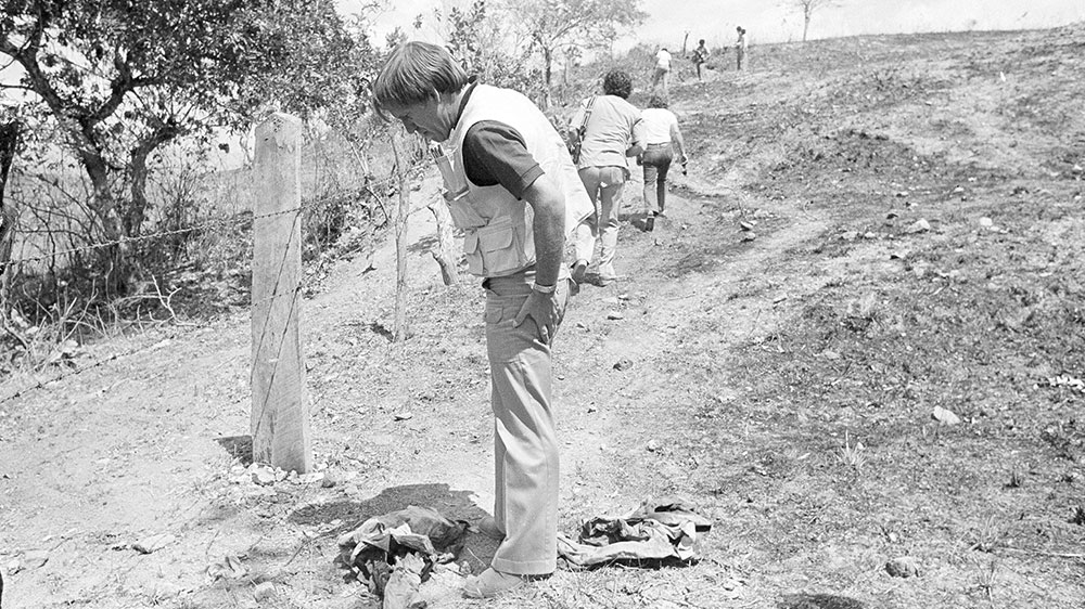 Television cameramen photograph blood-soaked, bullet-ridden clothes believed to belong to four Dutch journalists killed in a wooded area near this village in the province of Chalatenango [File: PW Hamilton/AP]